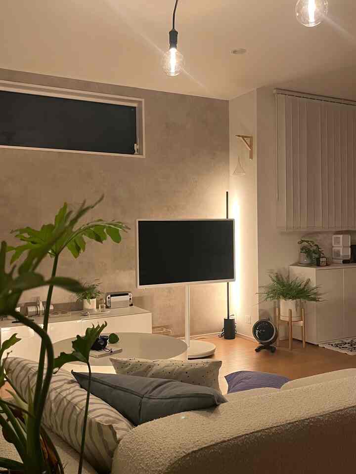 暖かいホワイトとブラウンの色調のリビング、クリーム色のソファと丸いテーブル、フロアランプが配置された雰囲気のある空間