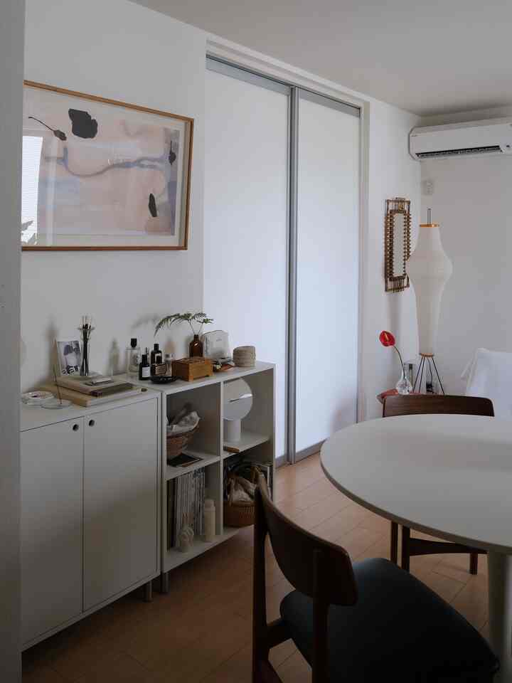 白と木目調のダイニング、丸テーブルと椅子、収納家具が配置されたシンプルな空間