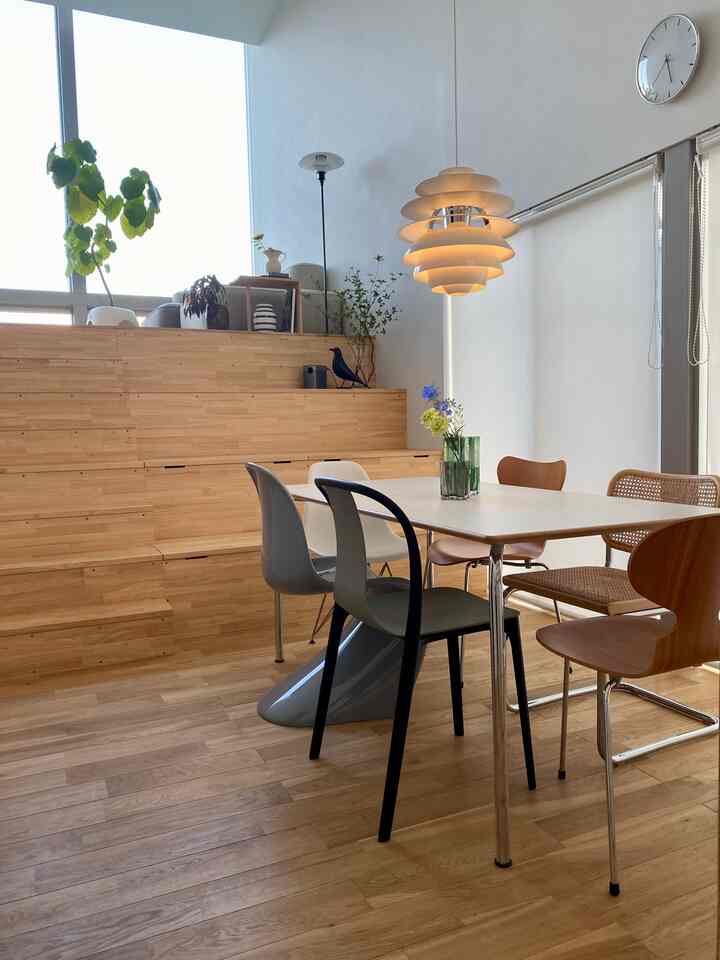 木目調のナチュラルなダイニングルーム、様々なデザインのダイニングチェアとペンダントライトが配置された印象的な空間