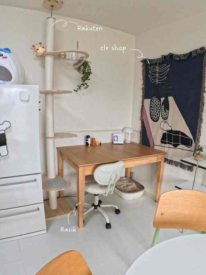 ホワイトとウッドトーンが基調の小さなワンルーム、猫のキャットタワーとデスクが配置された雰囲気のあるホームオフィス空間