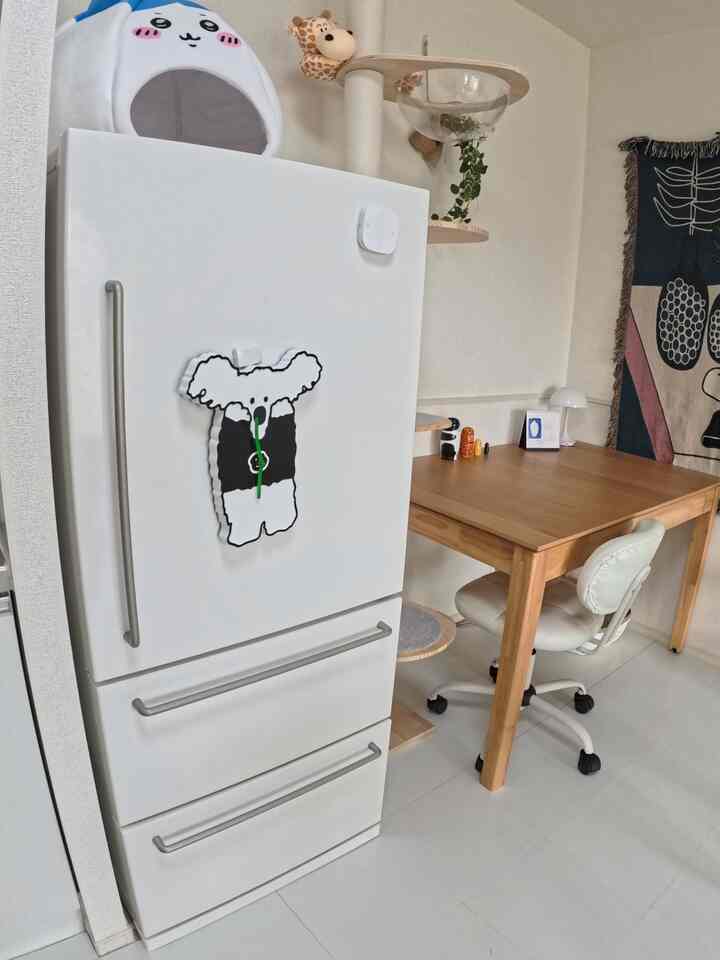 白とナチュラルカラーのキッチン空間、冷蔵庫とデスク、キャットタワーが配置された雰囲気のあるインテリア