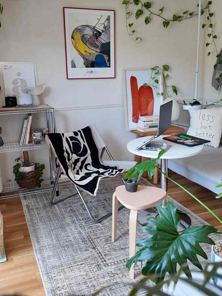 Natural-tone Nordic living room featuring a round table with laptop and surrounding plants in a cozy workspace