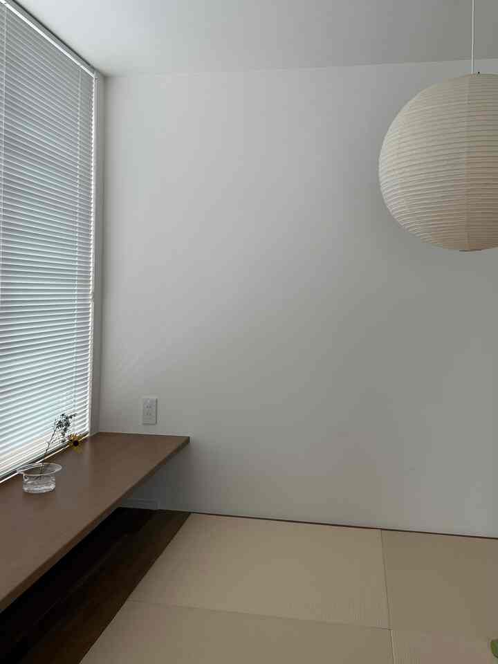 白い壁と畳がある静かで清潔感のある小さな和室、木目調のベンチと和紙のペンダントライトが配置された印象的な空間