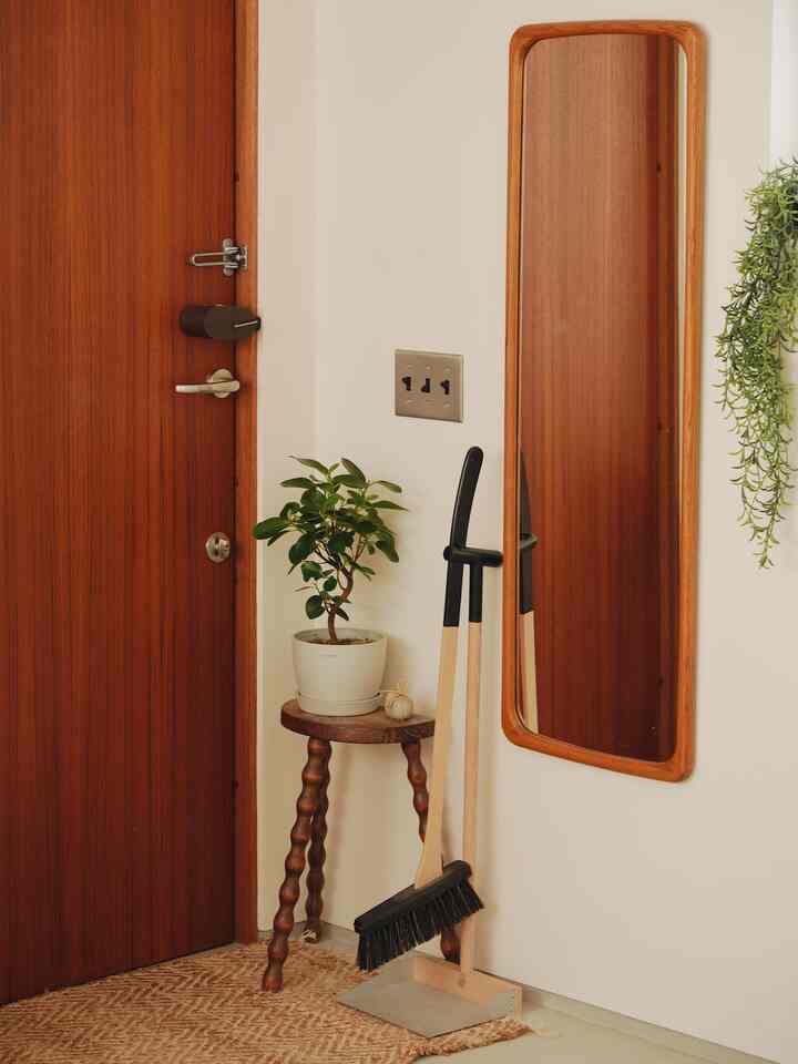 Natural-toned entrance featuring a wooden door and stool with a plant, creating a cozy atmosphere