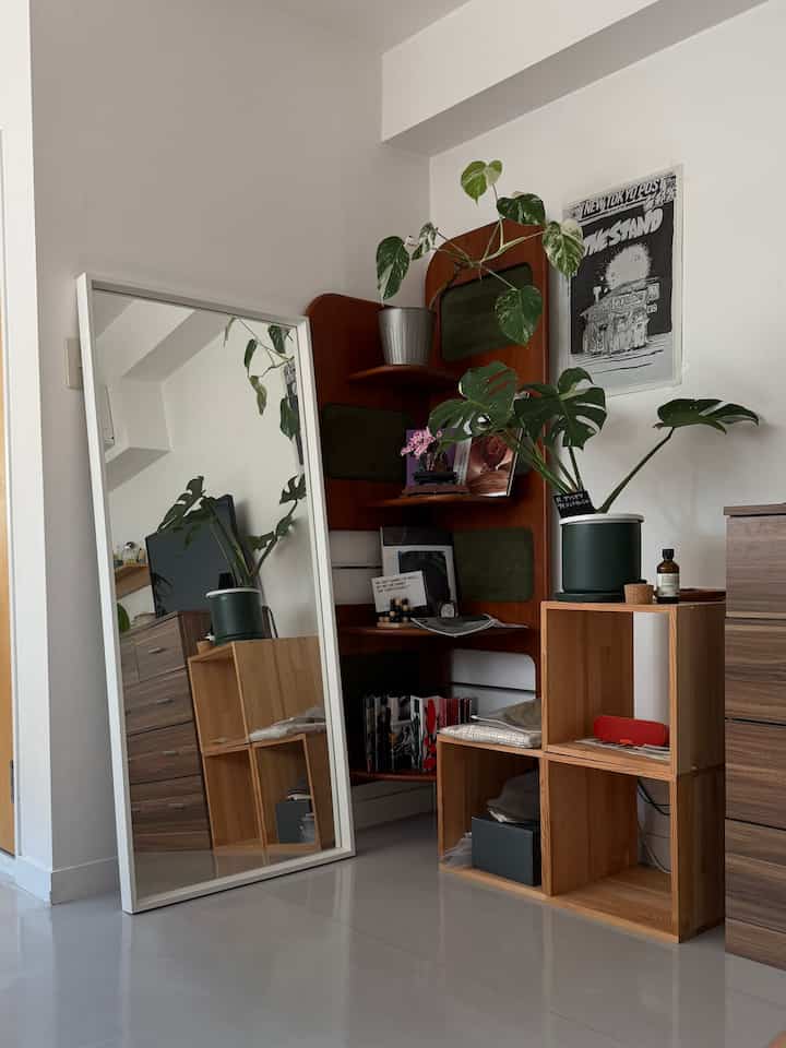 白い壁と木目調の家具、植物が配置されたコンパクトなコーナー収納のある空間