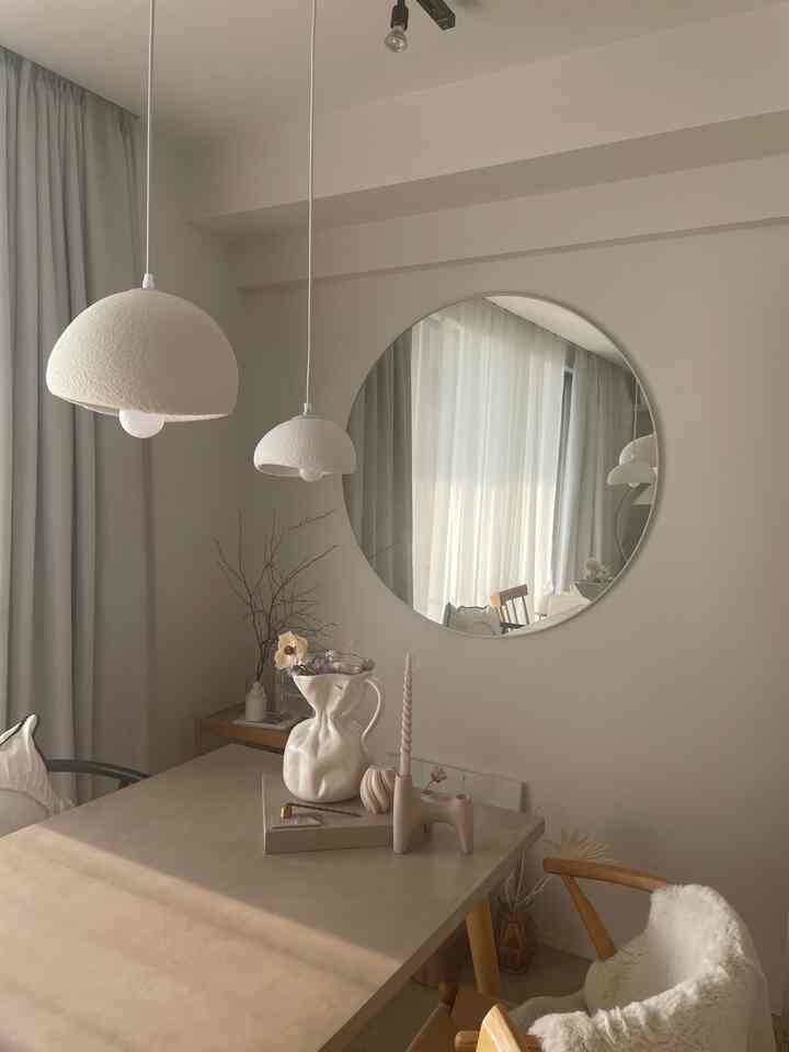 白とベージュの色調のダイニング、ペンダントライトと丸い鏡が配置されたナチュラルモダンな雰囲気のインテリア