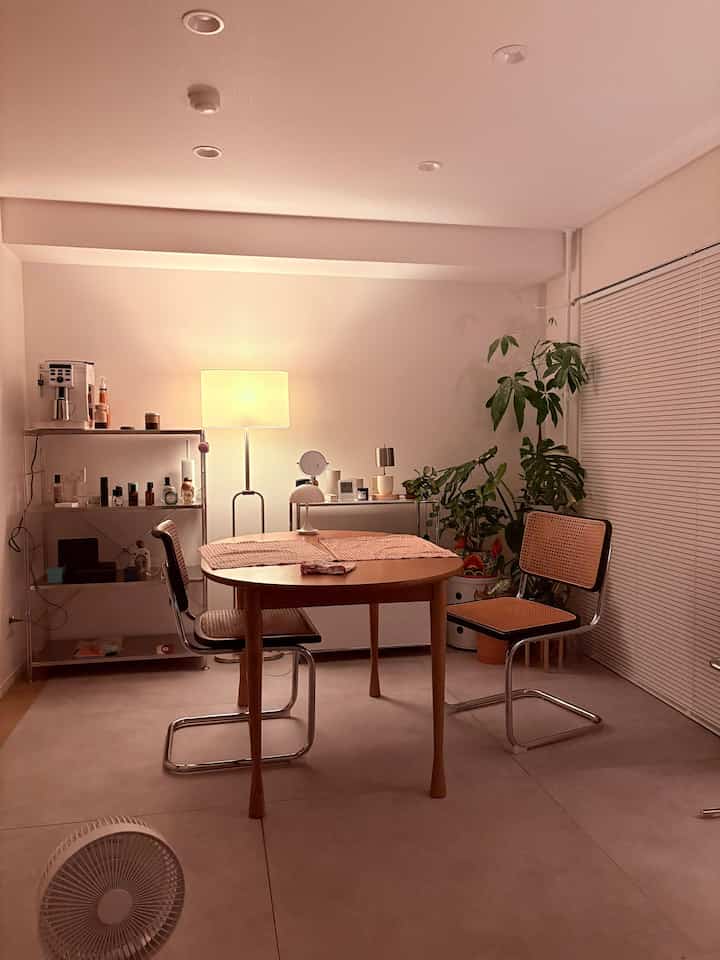 暖かい照明と丸い木製テーブル、ラタンのダイニングチェアがある二人用のダイニングルーム