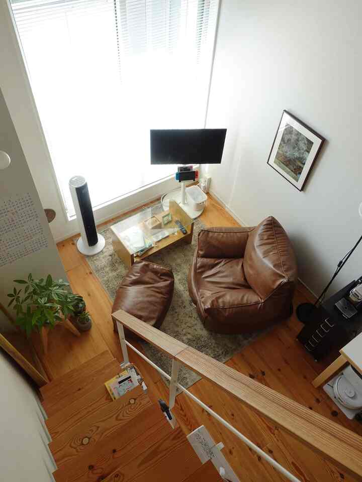 明るい色調のワンルームリビング、ブラウンのビーズクッションソファとガラステーブルが配置された雰囲気のある空間