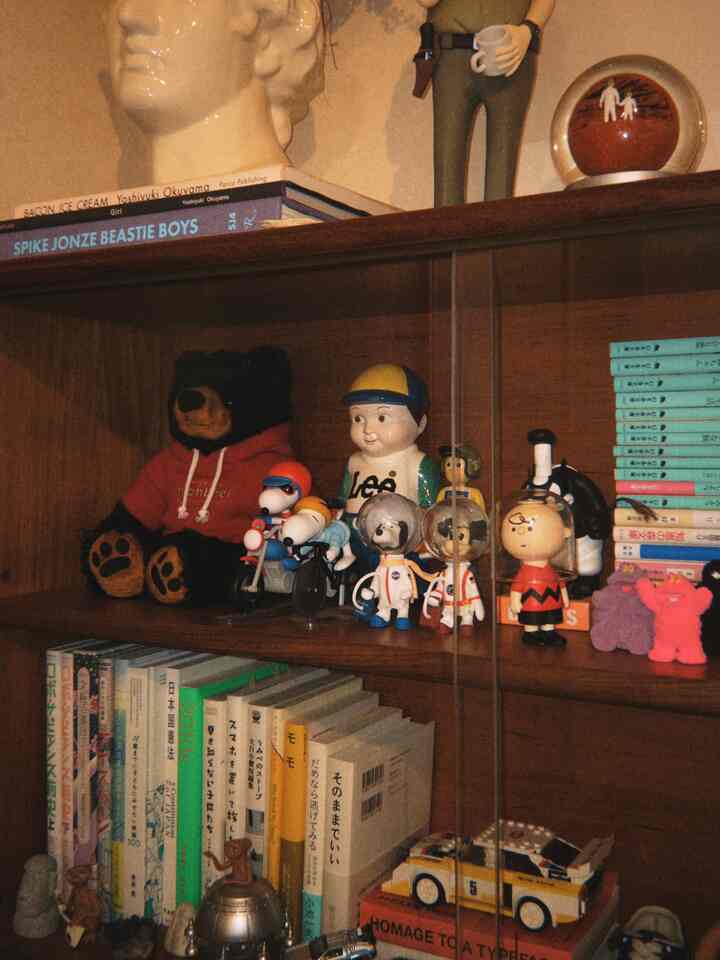 ブラウンの木製の本棚に様々なフィギュアと本が並べられたミッドセンチュリーモダンスタイルの飾り棚