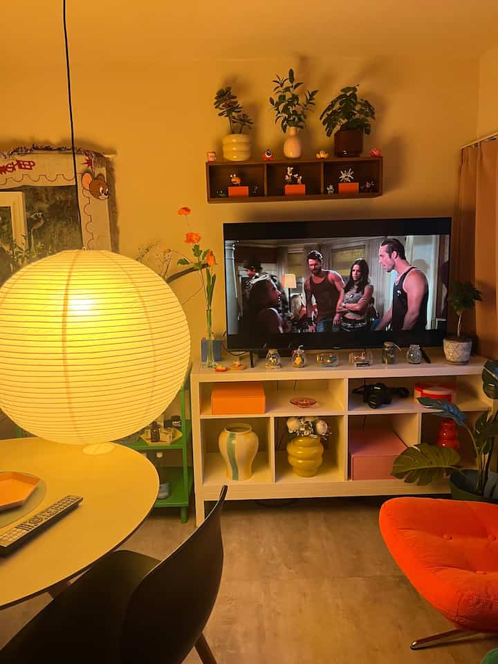 暖かい黄色とオレンジのトーンの1LDKリビング、花瓶とアームチェアが配置されたミッドセンチュリーモダンの雰囲気あるインテリア