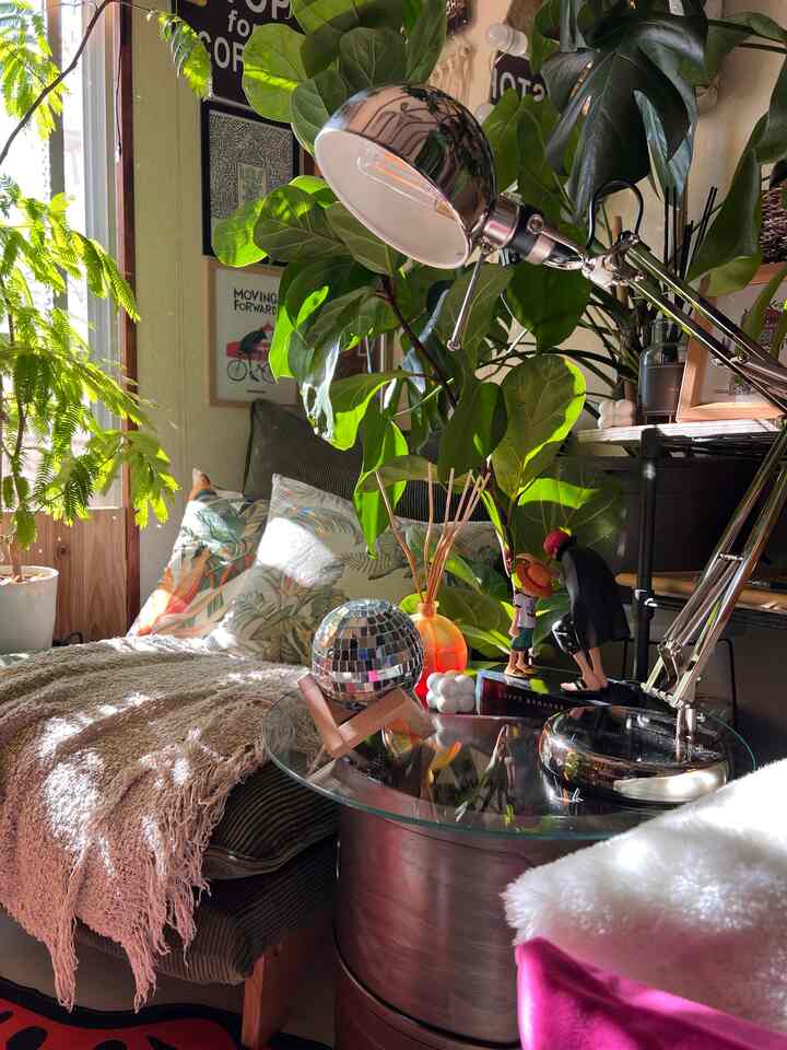 緑とナチュラルなトーンのリビング、クッションと植物が配置された落ち着いた雰囲気の空間