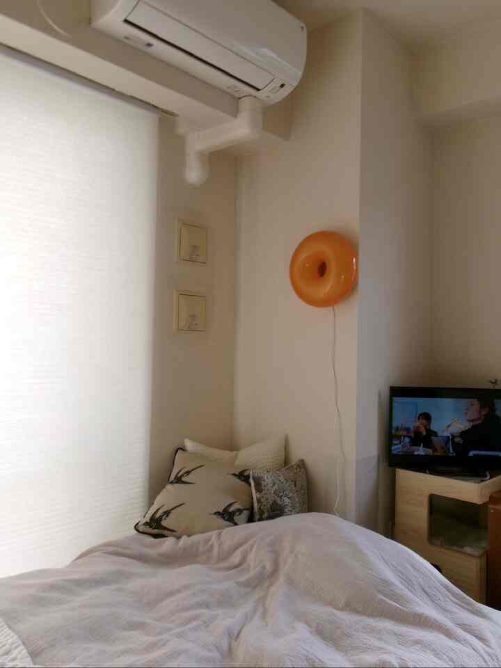 Beige bedding in a compact single bedroom featuring a cat tower with a cozy atmosphere