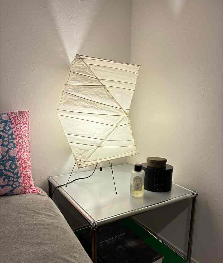 白とシルバーの色調の寝室、ナイトテーブルとイサム・ノグチのアカリフロアランプが配置されたミッドセンチュリーモダンなインテリア