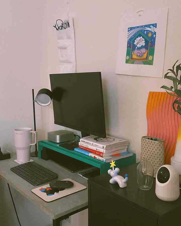 モダンな一人暮らしのホームオフィスワークスペース、グレーのデスクとモニターがあり、壁にアートと収納アイテムが配置されている