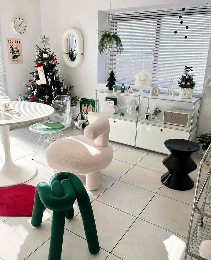 白と緑の色調のリビング、個性的な椅子とクリスマスツリーが配置された雰囲気のある空間