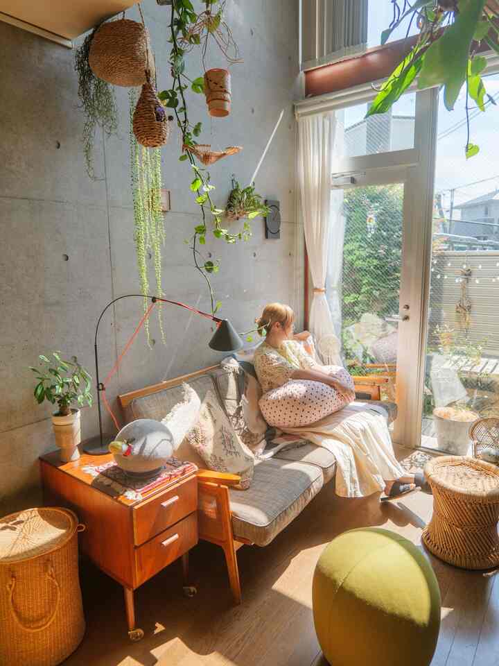 暖かな自然光と緑が調和するナチュラルなリビング、木目調家具とファブリックソファが配置された居心地の良い空間