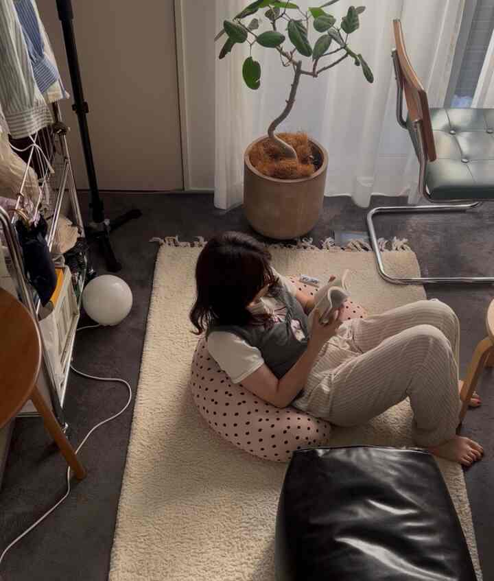 Bright cream rug with a pink polka-dot bean bag and plant in a modern small single household room featuring a person reading