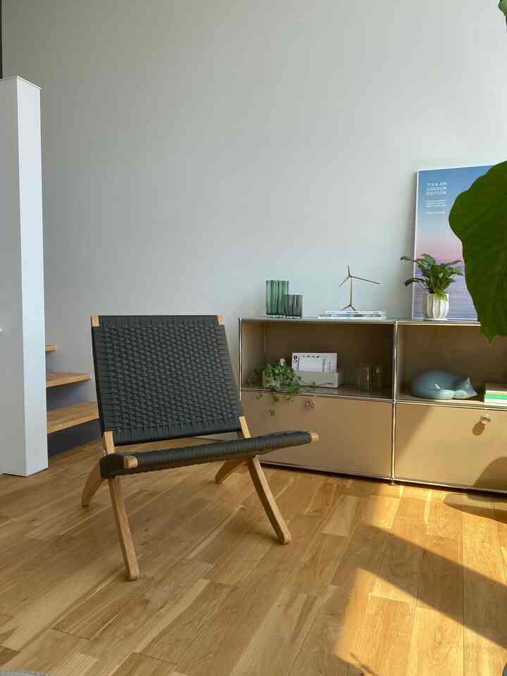 Bright natural color living room featuring wood tone flooring, an armchair, sideboard with a cat figurine for a warm atmosphere