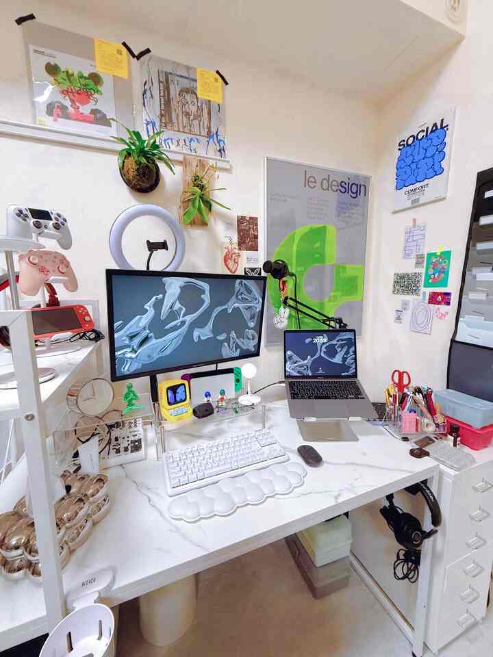 White-tone compact home office featuring desk with monitor, laptop, and various gaming devices in a neat workspace