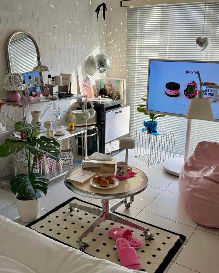 白とライトブラウンの色調のリビングルーム、丸テーブル、ミラーボール、ピンクのビーズクッションが配置されたモダンな印象的な空間