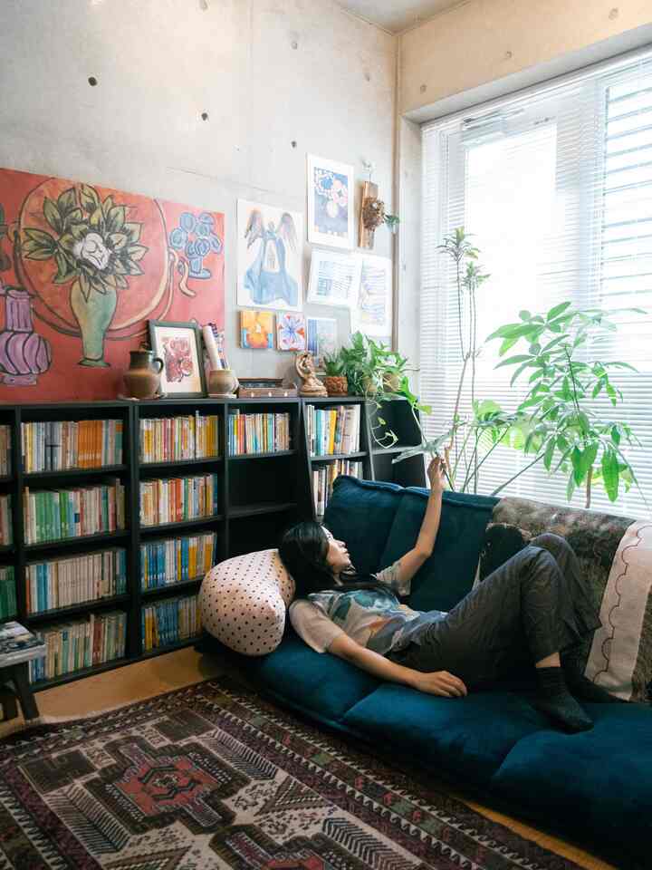 ネイビーカラーのビーズクッションソファと壁画、植物が配置されたヴィンテージ風のリビング