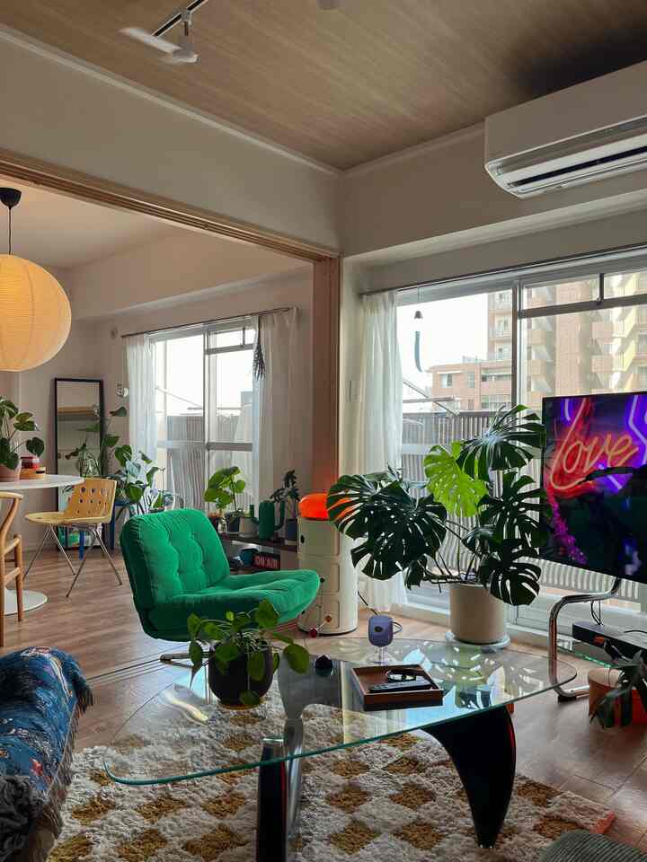 ホワイトとウッドトーンが調和した1LDKのリビングルーム、モンステラの植物とグリーンのアームチェアが印象的な自然の雰囲気あるインテリア