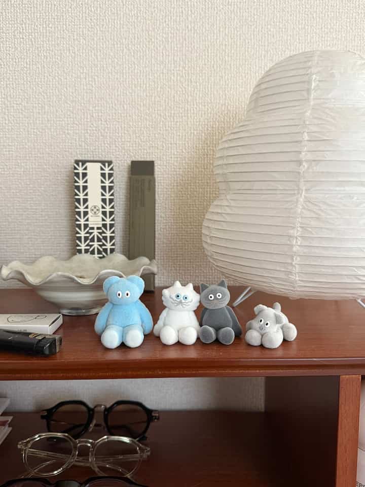 白い壁と大きな和紙ランプ、木製の棚に小さな動物のオブジェが並ぶミニマルなインテリア