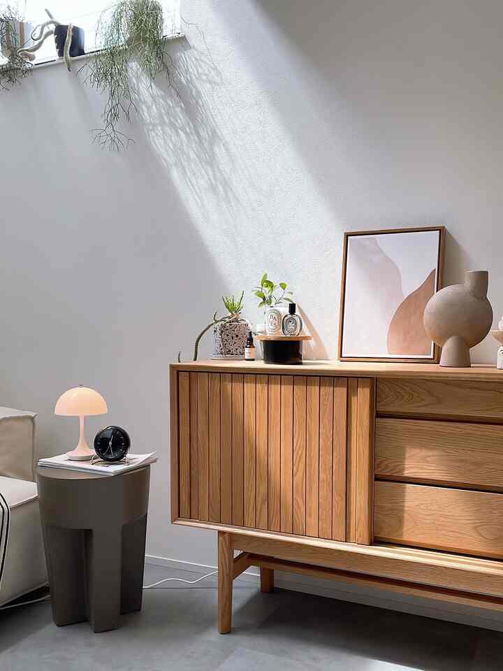 明るい白い壁とナチュラルな木目調のキャビネットが配置されたミニマルな北欧風リビング