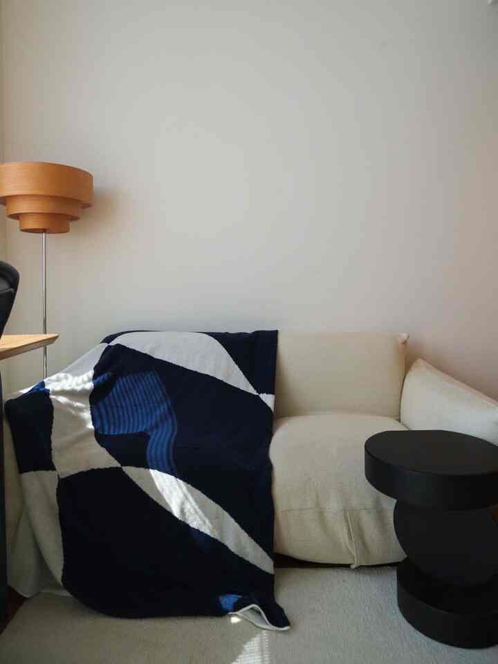 Cozy living room featuring navy and white throw on beige sofa with natural wood floor lamp