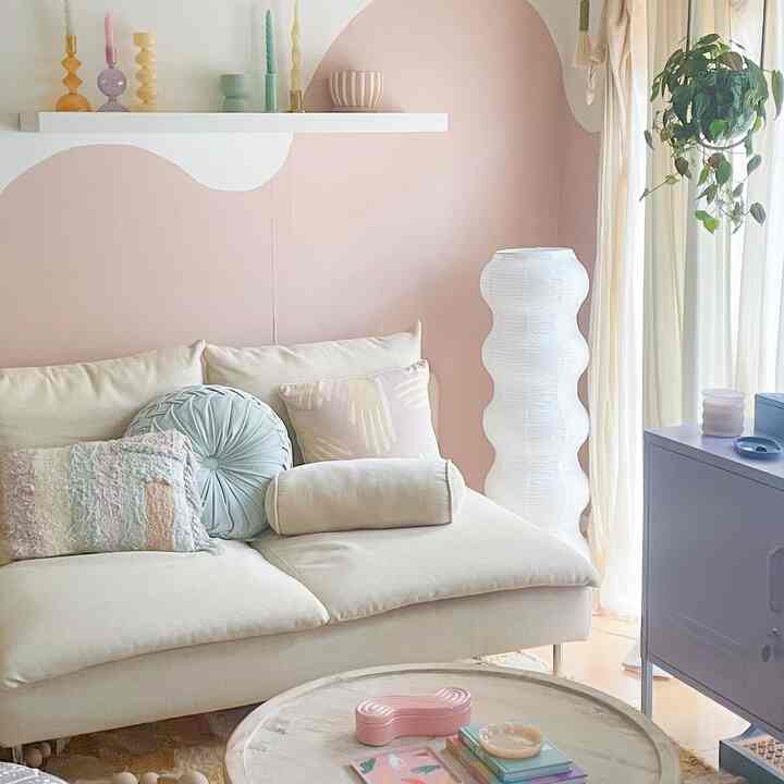 柔らかいベージュとパステル調の壁がある居心地の良いリビング、ベージュのソファと丸いコーヒーテーブルが配置されたナチュラルな雰囲気のインテリア