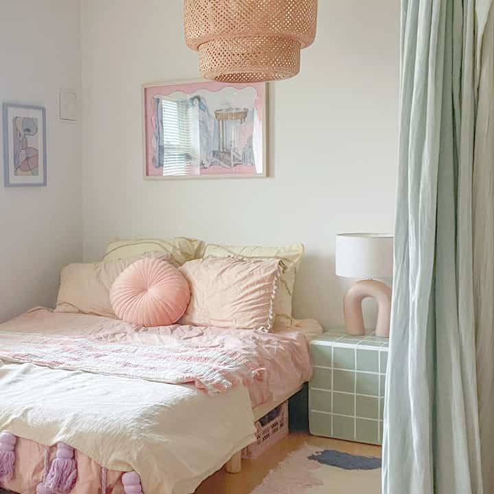 ピンクと白のトーンの一人暮らし寝室、ベッドとペンダントライトが温かみのある雰囲気を醸し出すインテリア