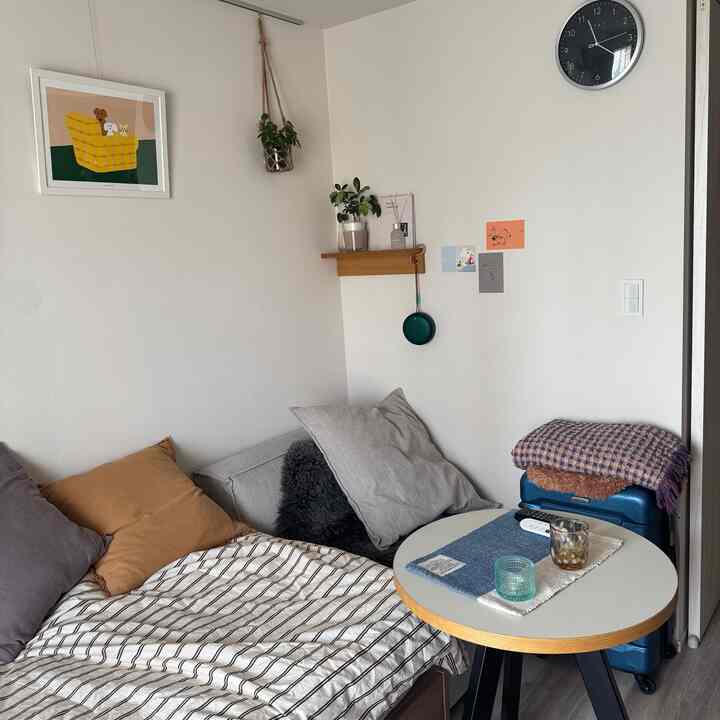 Beige and gray toned single household bedroom featuring a sofa bed and small round coffee table in a simple, natural space
