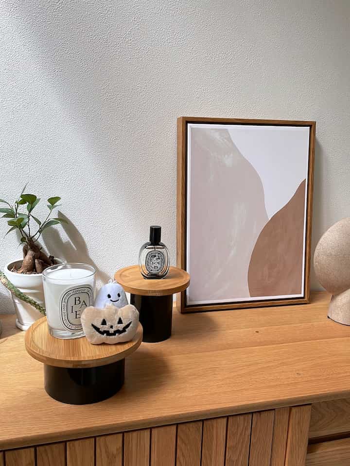 ナチュラルな木目調のキャビネットの上にキャンドルとポスターが配置された、北欧風のシンプルなリビング空間