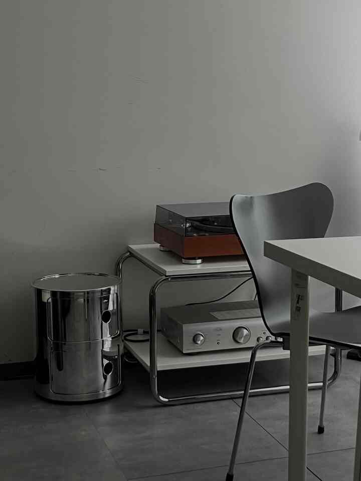 Modern space in white and gray tones featuring an Ikea table with a record player and amplifier arranged simply