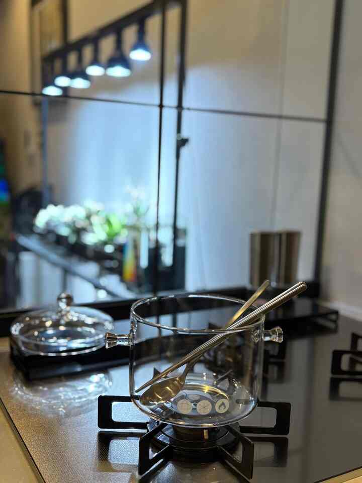 透明なガラス鍋と金属製カトラリーが置かれた、モダンで洗練されたキッチンスペース