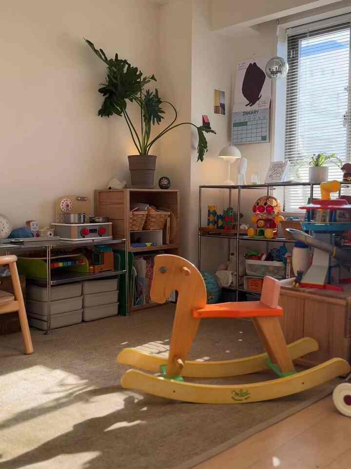 ナチュラルな色調の子供部屋、木製のロッキングホースと棚に多様なおもちゃが置かれた雰囲気のある空間