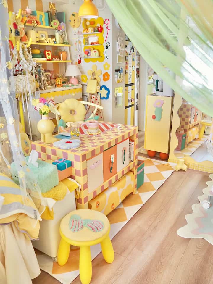 明るい黄色のトーンが特徴のキッチンスペース、多彩な家具と装飾が配置された雰囲気のあるカフェ風インテリア