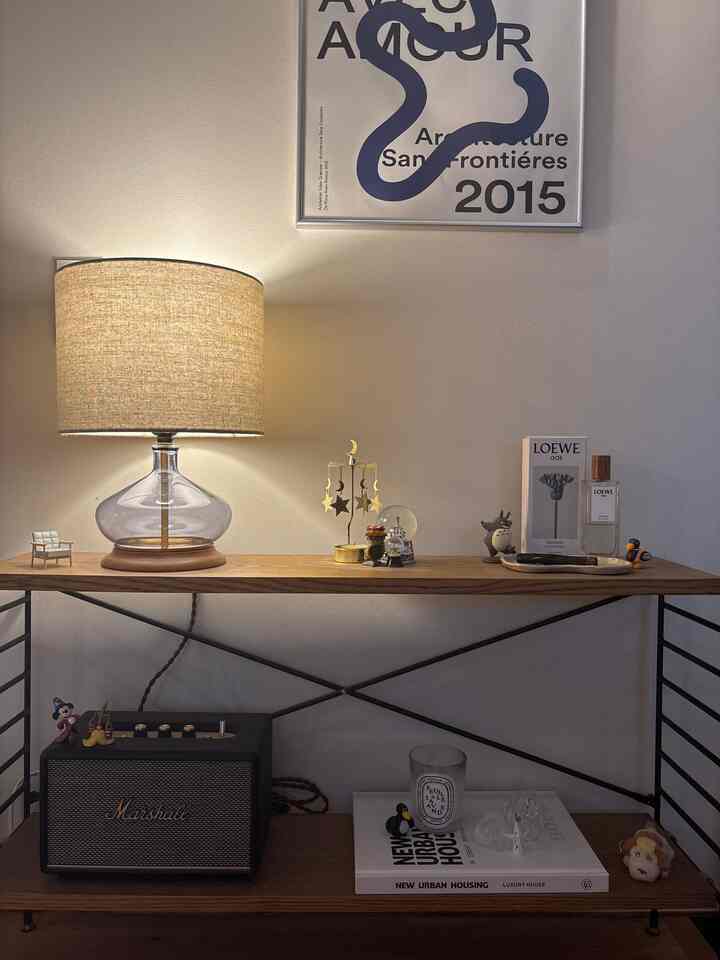 Natural color and wood-toned Nordic style wall shelving featuring a table lamp and various objets creating a cozy interior space