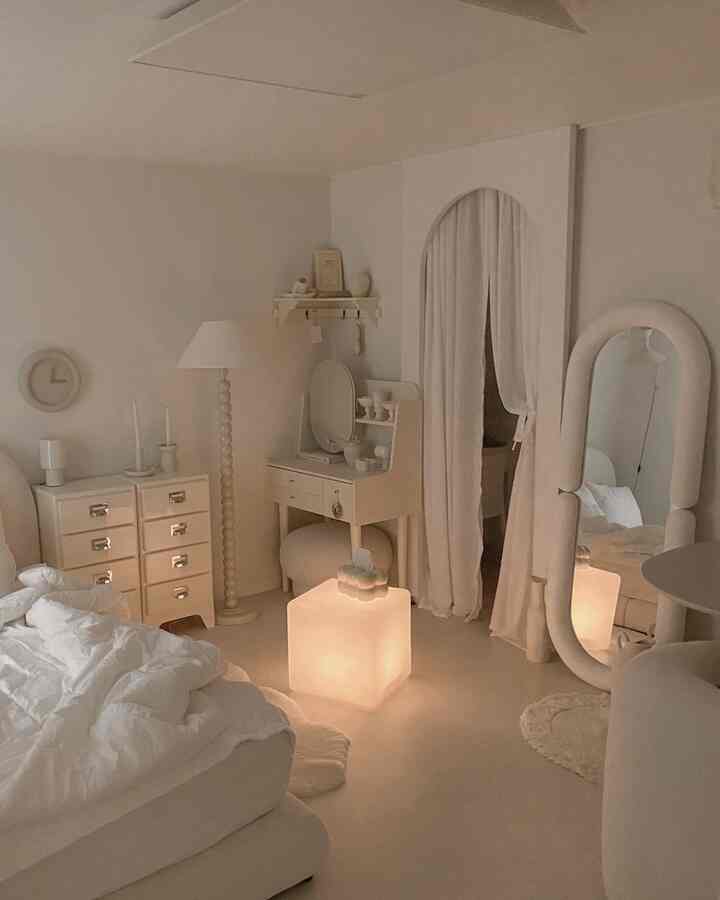 柔らかなホワイトトーンの寝室、アーチ状の間仕切り壁ときれいなポケットカーテン、大きな全身鏡とミニマルな家具配置