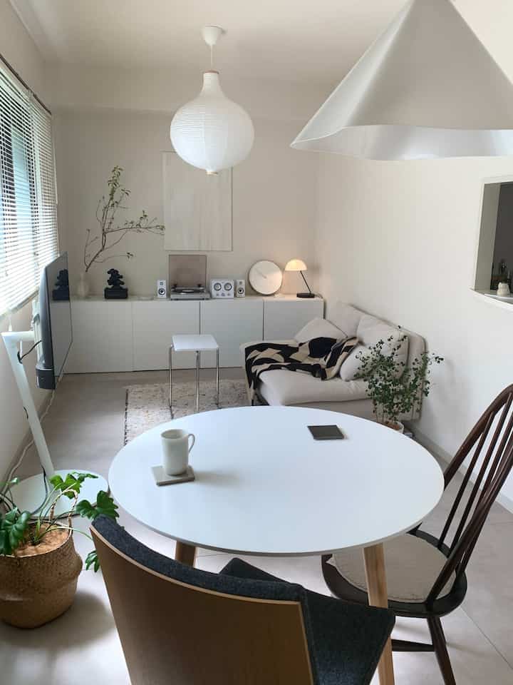 White-toned 12-tatami living and dining room featuring a round dining table, sofa, and plants with a clean natural modern vibe