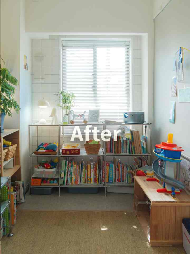 白とナチュラルカラーの子供部屋、中央の窓にブラインドがあり、本棚には子供の本とおもちゃが整然と配置された明るいインテリア