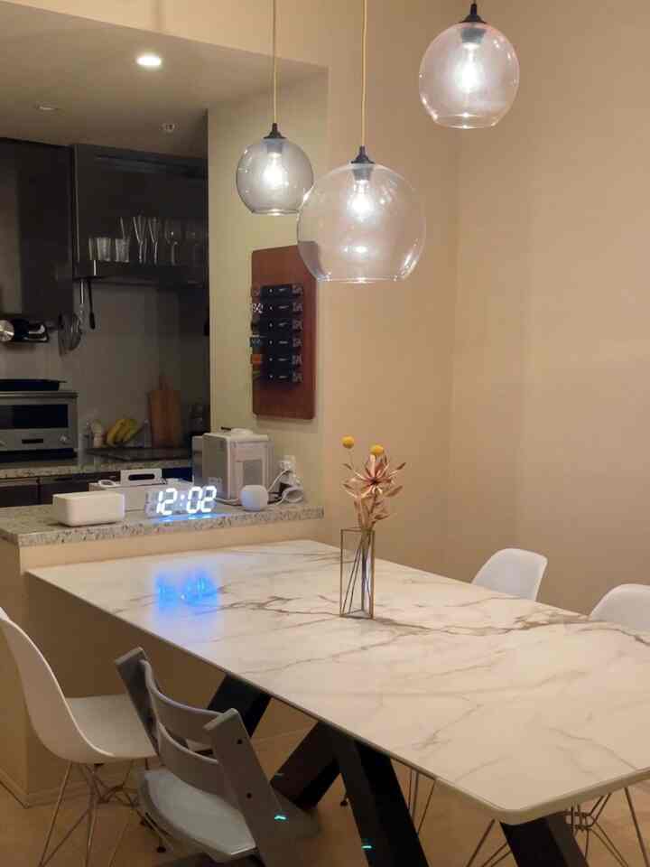 ベージュの壁と大理石のダイニングテーブルが配置されたモダンなダイニングルーム、ペンダントライトが雰囲気を演出