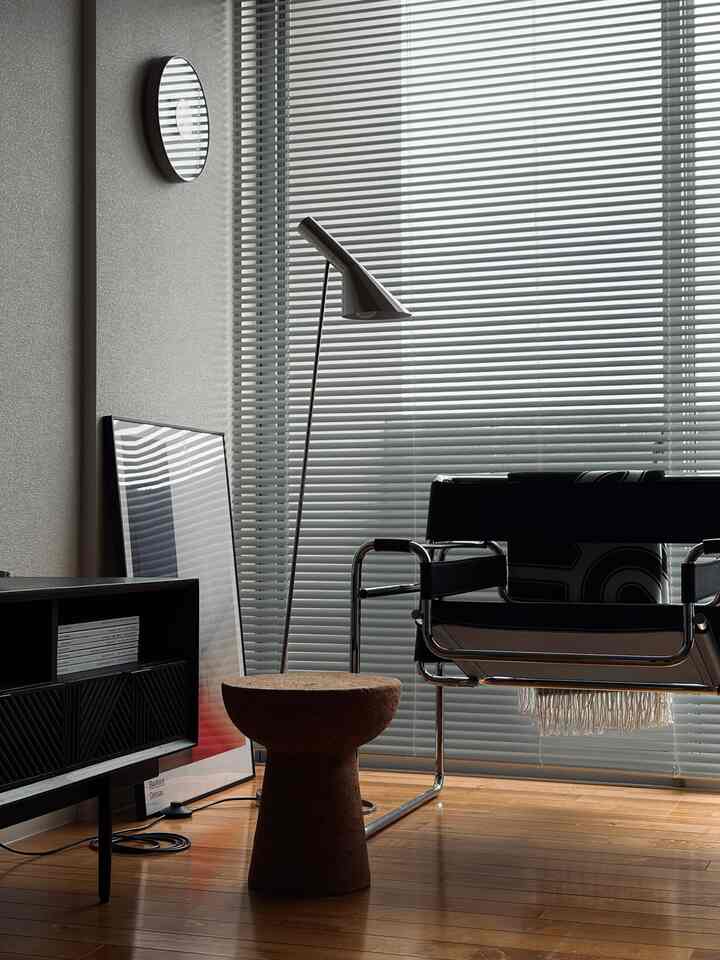 木目調の床とモダンなフロアランプ、黒いアームチェアが配置された雰囲気のあるリビング