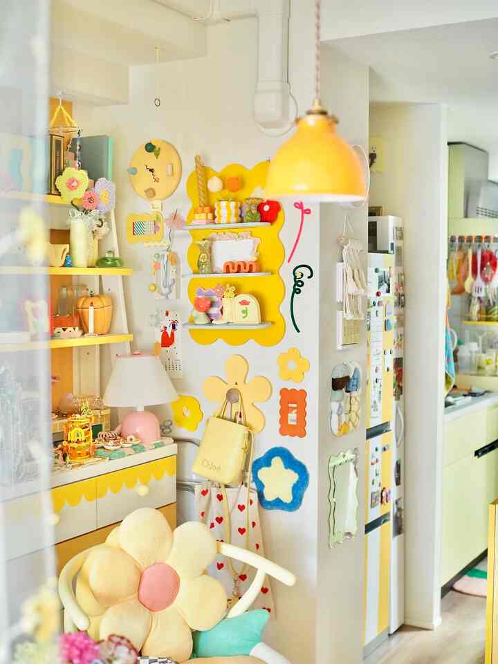 明るくカラフルな黄色を基調としたリビングとキッチンの空間、花型クッションや小物が配置された雰囲気のあるインテリア