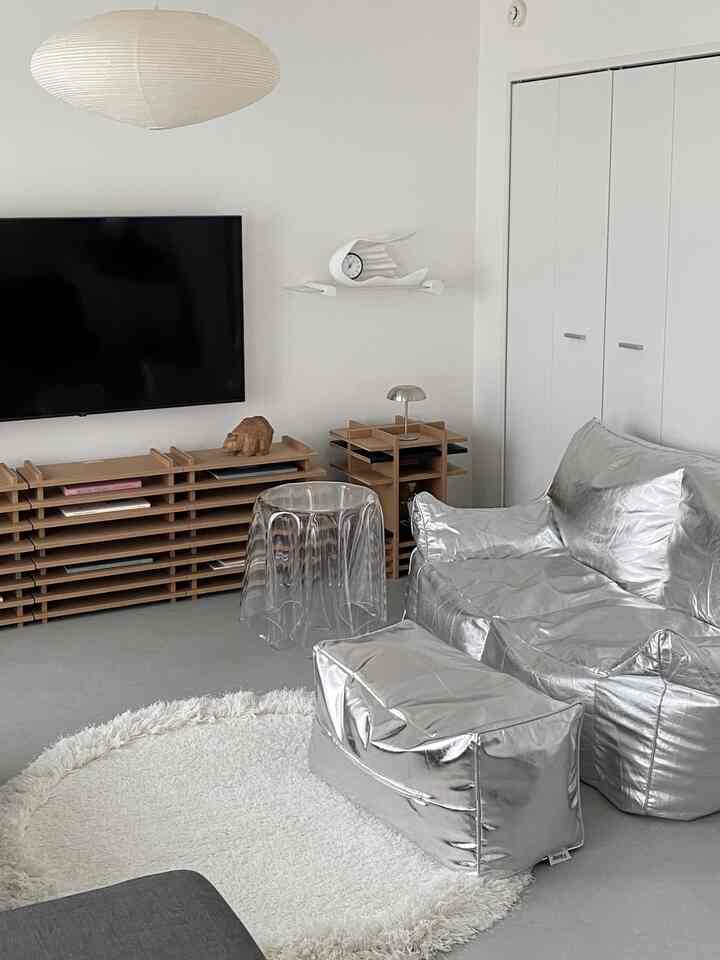 シルバーのビーズクッションソファとオットマンが配置された、ホワイトトーンのすっきりとしたリビングルーム