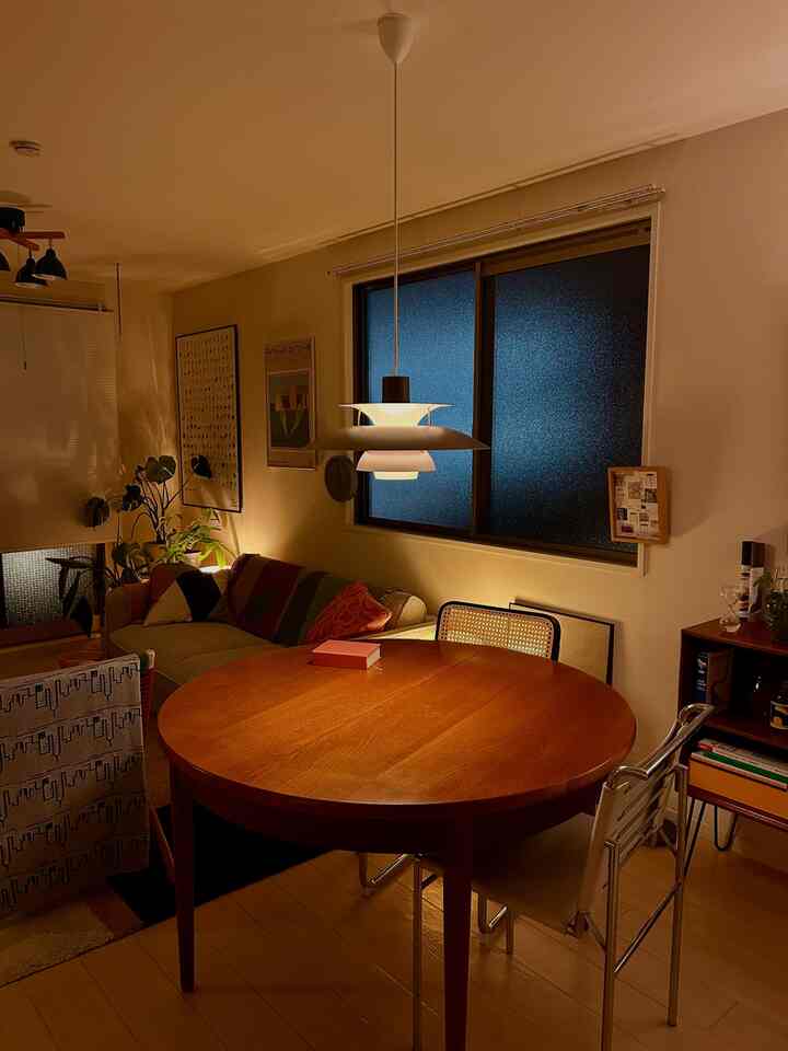 暖かいナチュラルトーンのダイニング、ラウンド木製テーブルとペンダントライトが配置された居心地の良いインテリア