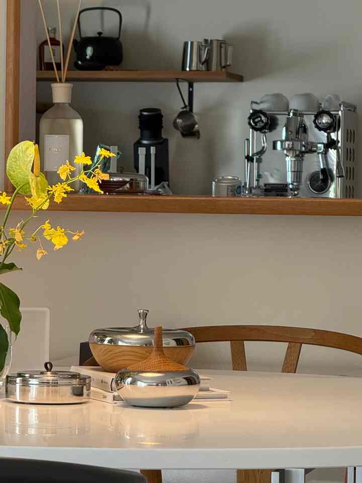 ウッドトーンとシルバーが調和したキッチン、エスプレッソマシンと調理器具が配置された雰囲気のあるホームカフェ空間