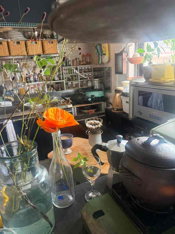Natural-toned kitchen featuring coffee tools and vibrant orange flower creating a cozy, inviting atmosphere