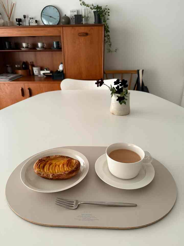 白と木目調が調和したダイニングルーム、シンプルなテーブルにティーカップとペストリーが置かれたおうちカフェの雰囲気のあるインテリア