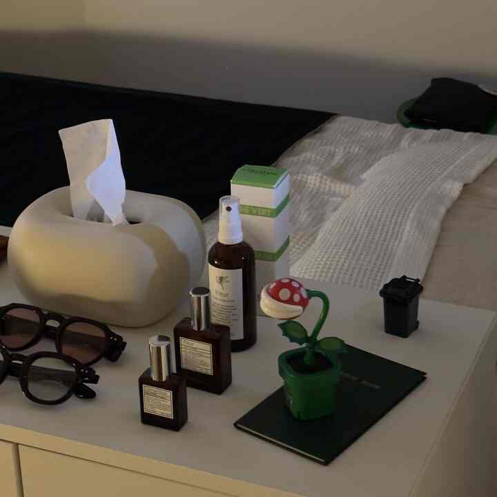 White and green toned bedroom featuring neat bedding and a nightstand with small decorative items in a modern atmosphere